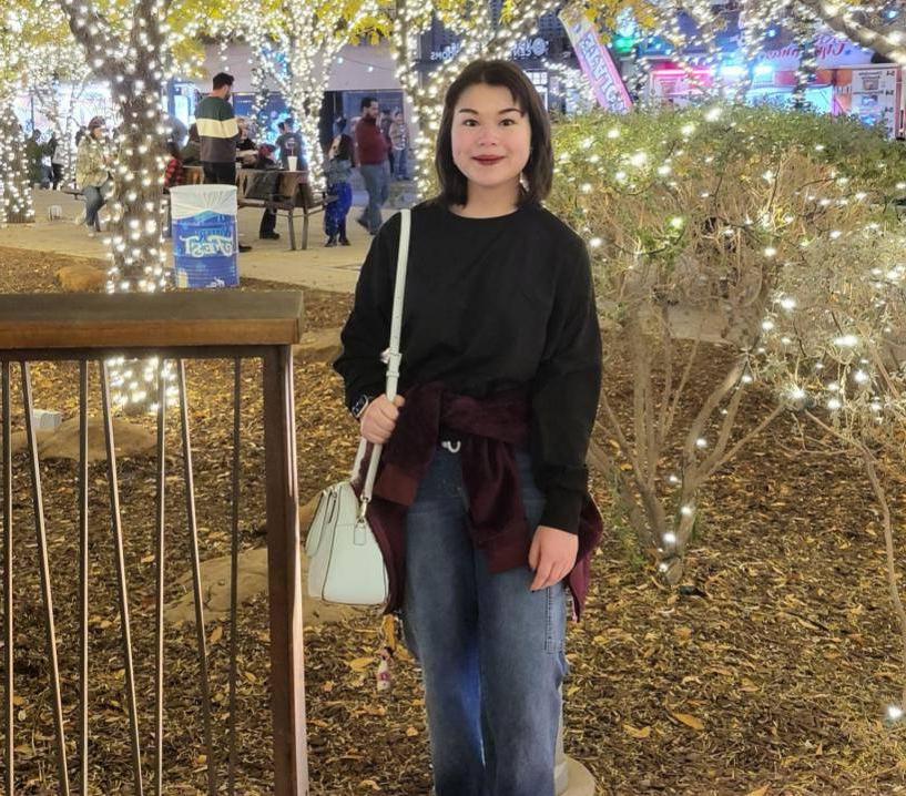 Girl standing under trees decorated with lights